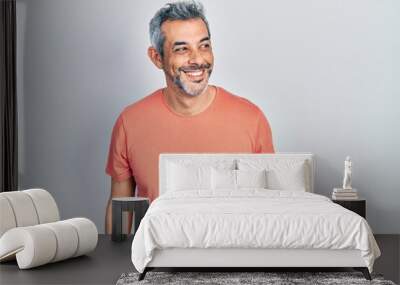 Handsome middle age man with grey hair wearing casual t shirt looking away to side with smile on face, natural expression. laughing confident. Wall mural