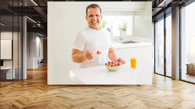 Handsome middle age senior man eating healthy cereals for breakfast in the morning Wall mural