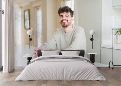 Handsome young man smiling cheerful at the camera with a big smile on face showing teeth Wall mural