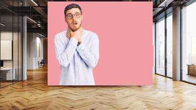 Handsome young man with bear wearing elegant business shirt and glasses shouting suffocate because painful strangle. health problem. asphyxiate and suicide concept. Wall mural