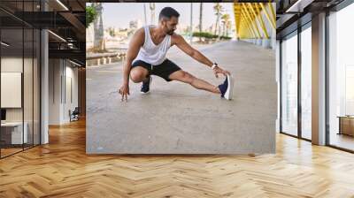 Hispanic man stretching after working out outdoors on a sunny day Wall mural