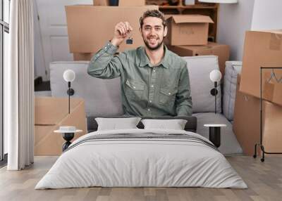 Hispanic man with beard holding keys of new home looking positive and happy standing and smiling with a confident smile showing teeth Wall mural