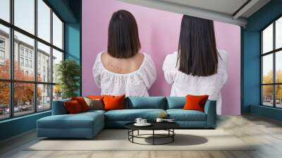 Hispanic mother and daughter together standing backwards looking away with crossed arms Wall mural