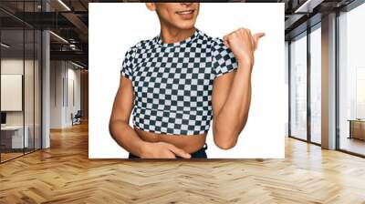 Hispanic transgender man wearing make up and long hair wearing modern clothes smiling with happy face looking and pointing to the side with thumb up. Wall mural