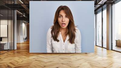 Hispanic woman standing over isolated background afraid and shocked with surprise and amazed expression, fear and excited face. Wall mural