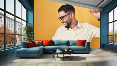 Hispanic young man wearing business clothes and glasses dancing happy and cheerful, smiling moving casual and confident listening to music Wall mural