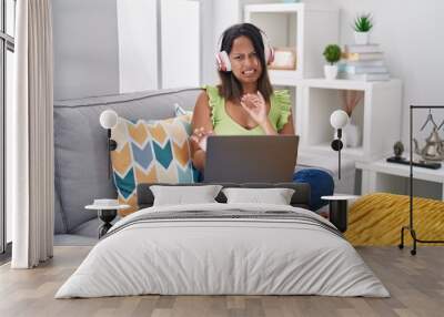 Hispanic young woman using laptop at home disgusted expression, displeased and fearful doing disgust face because aversion reaction. with hands raised Wall mural