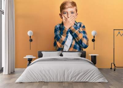 Little caucasian boy kid wearing casual clothes shocked covering mouth with hands for mistake. secret concept. Wall mural