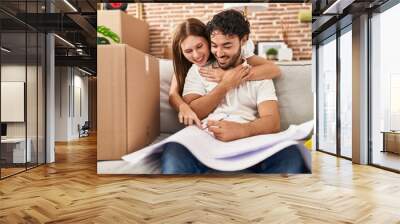 Man and woman couple hugging each other looking house plans at new home Wall mural