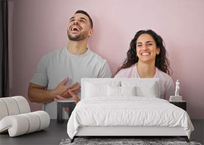 Man and woman couple laughing a lot standing together over isolated pink background Wall mural