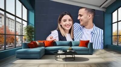 Man and woman couple smiling confident hugging each other over black background Wall mural