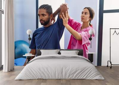 Man and woman wearing physiotherapist uniform having rehab session stretching arm at physiotherpy clinic Wall mural