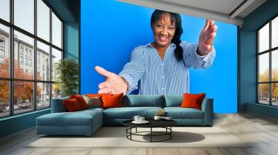 Middle age african american woman wearing casual clothes looking at the camera smiling with open arms for hug. cheerful expression embracing happiness. Wall mural