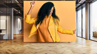 Middle age african american woman wearing wool winter sweater and leather jacket dancing happy and cheerful, smiling moving casual and confident listening to music Wall mural