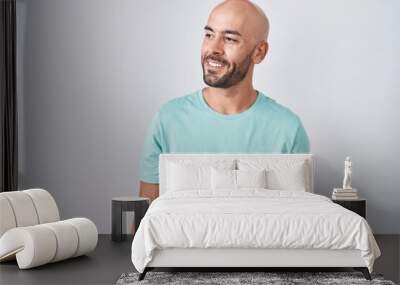 Middle age bald man standing over white background looking away to side with smile on face, natural expression. laughing confident. Wall mural