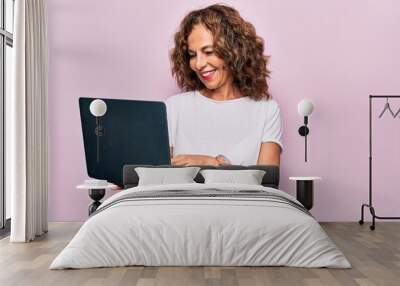 Middle age beautiful business woman working using laptop over isolated pink background looking positive and happy standing and smiling with a confident smile showing teeth Wall mural