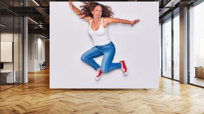 Middle age beautiful hispanic woman wearing casual clothes smiling happy. Jumping with smile on face over isolated white background Wall mural