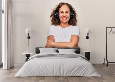 Middle age beautiful woman listening to music using headphones over white background happy face smiling with crossed arms looking at the camera. Positive person. Wall mural