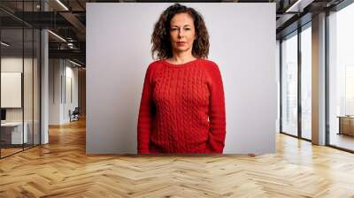 Middle age brunette woman wearing casual sweater standing over isolated white background Relaxed with serious expression on face. Simple and natural looking at the camera. Wall mural