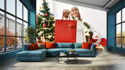 Middle age caucasian woman smiling confident holding christmas gift bag at home Wall mural