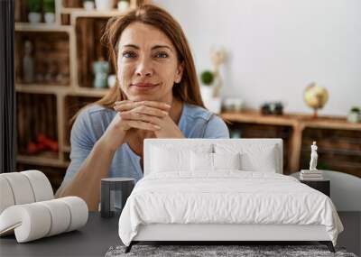 Middle age caucasian woman smiling happy sitting on the table at home. Wall mural