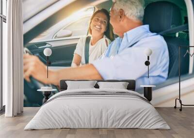 Middle age couple in love sitting inside the car going for a trip smiling happy and cheerful together Wall mural