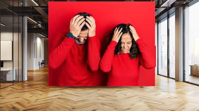 Middle age couple of hispanic woman and man hugging and standing together suffering from headache desperate and stressed because pain and migraine. hands on head. Wall mural