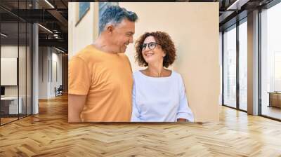 Middle age couple smiling happy leaning on the wall at street of city. Wall mural