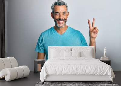 Middle age grey-haired man wearing casual clothes showing and pointing up with fingers number two while smiling confident and happy. Wall mural