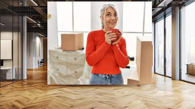 Middle age grey-haired woman smiling confident drinking coffee at new home Wall mural