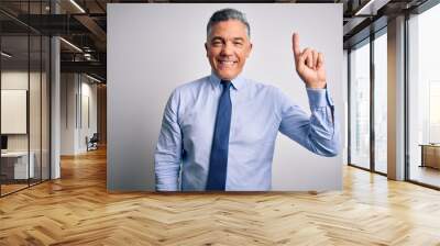 Middle age handsome grey-haired business man wearing elegant shirt and tie showing and pointing up with finger number one while smiling confident and happy. Wall mural