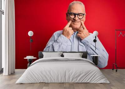 Middle age handsome hoary man wearing casual striped shirt and glasses over red background Smiling with open mouth, fingers pointing and forcing cheerful smile Wall mural