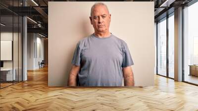 Middle age handsome hoary man wearing t-shirt standing over isolated white background with serious expression on face. Simple and natural looking at the camera. Wall mural