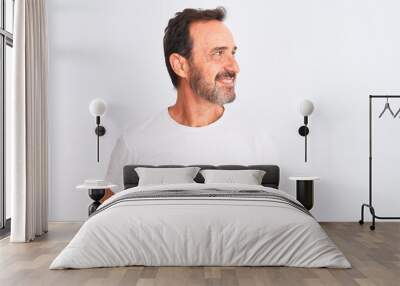 Middle age handsome man wearing casual t-shirt standing over isolated white background looking away to side with smile on face, natural expression. Laughing confident. Wall mural