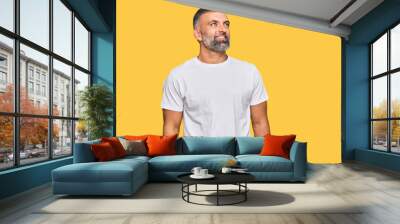 Middle age handsome man wearing casual white tshirt looking away to side with smile on face, natural expression. laughing confident. Wall mural