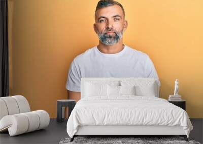 Middle age handsome man wearing casual white tshirt relaxed with serious expression on face. simple and natural looking at the camera. Wall mural