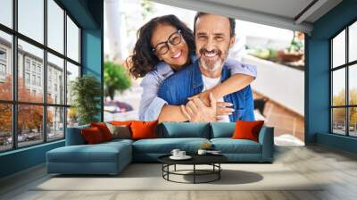 Middle age hispanic couple smiling confident hugging each other sitting on hammock at terrace Wall mural