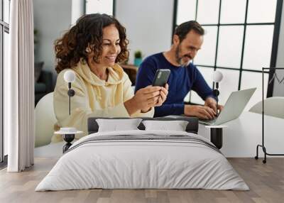 Middle age hispanic couple smiling happy using laptop and smartphone at home. Wall mural