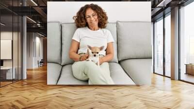 Middle age hispanic woman smiling confident holding chihuahua at home Wall mural