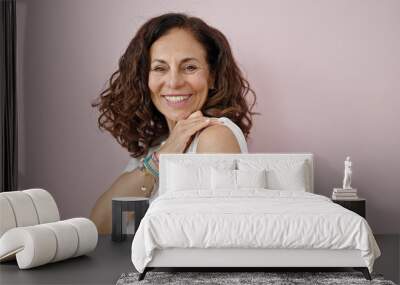 Middle age hispanic woman smiling confident standing with band aid on arm over isolated pink background Wall mural