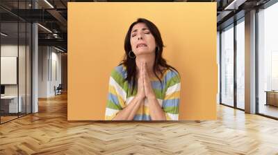 Middle age hispanic woman standing over yellow background begging and praying with hands together with hope expression on face very emotional and worried. begging. Wall mural