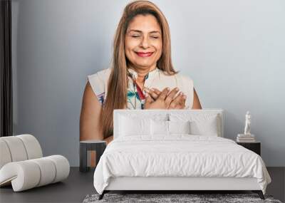 Middle age hispanic woman wearing casual clothes smiling with hands on chest with closed eyes and grateful gesture on face. health concept. Wall mural