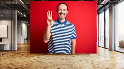 Middle age hoary man wearing casual striped polo standing over isolated red background showing and pointing up with fingers number three while smiling confident and happy. Wall mural