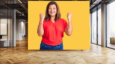 Middle age latin woman wearing casual clothes screaming proud, celebrating victory and success very excited with raised arms Wall mural