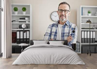 Middle age man business worker standing with arms crossed gesture and serious expression at office Wall mural