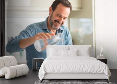 Middle age man drinking a glass of water with a happy face standing and smiling with a confident smile showing teeth Wall mural