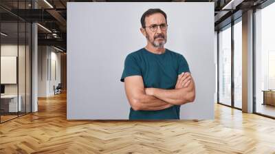 Middle age man standing with serious expression and arms crossed gesture over isolated white background Wall mural