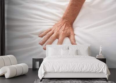 Middle age man touching bed sheet at bedroom Wall mural