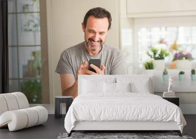 Middle age man using smartphone with a happy face standing and smiling with a confident smile showing teeth Wall mural