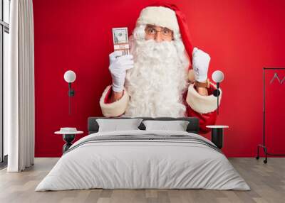 middle age man wearing santa claus costume holding dollars over isolated red background screaming pr Wall mural